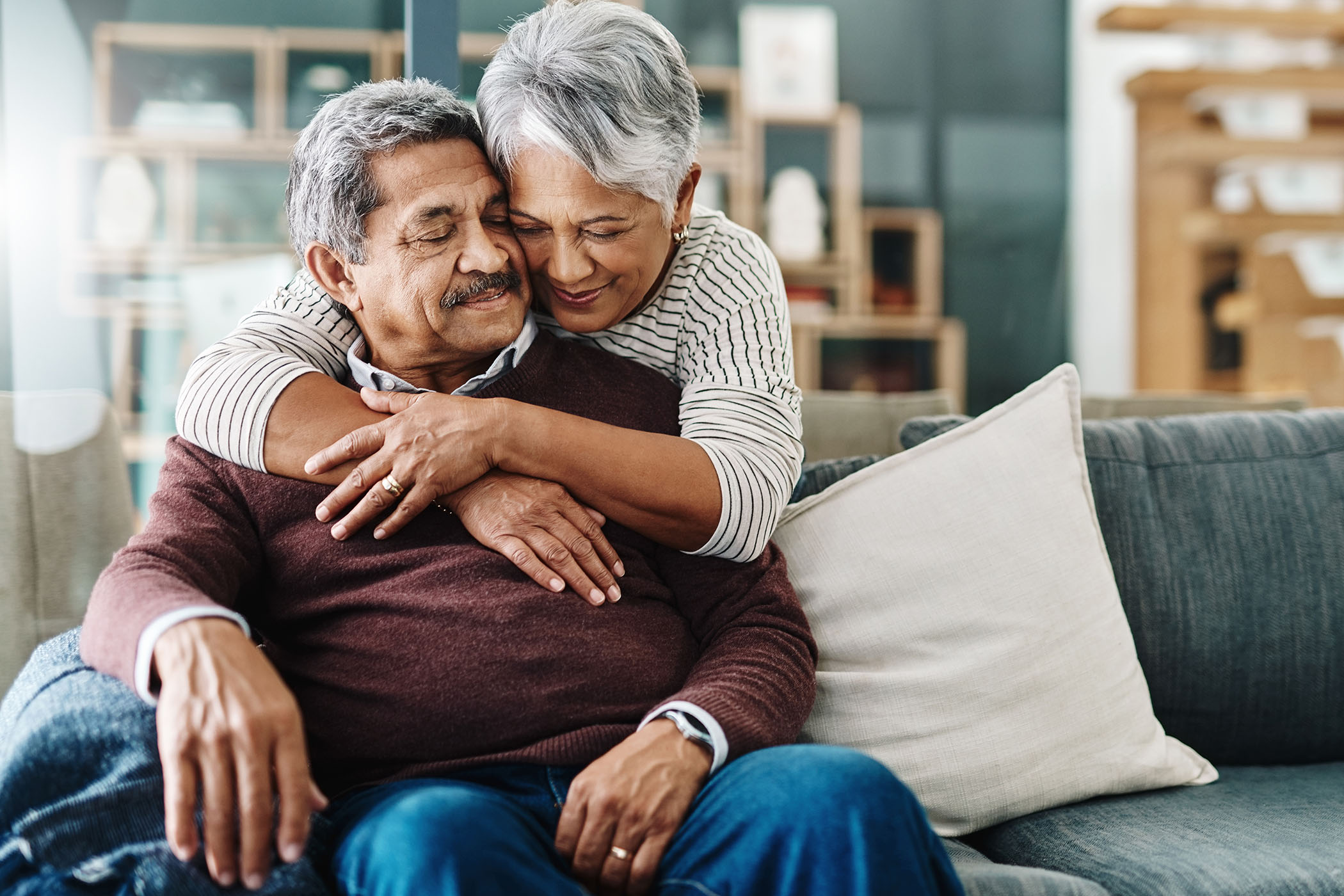 Older couple embracing while seated together at home.