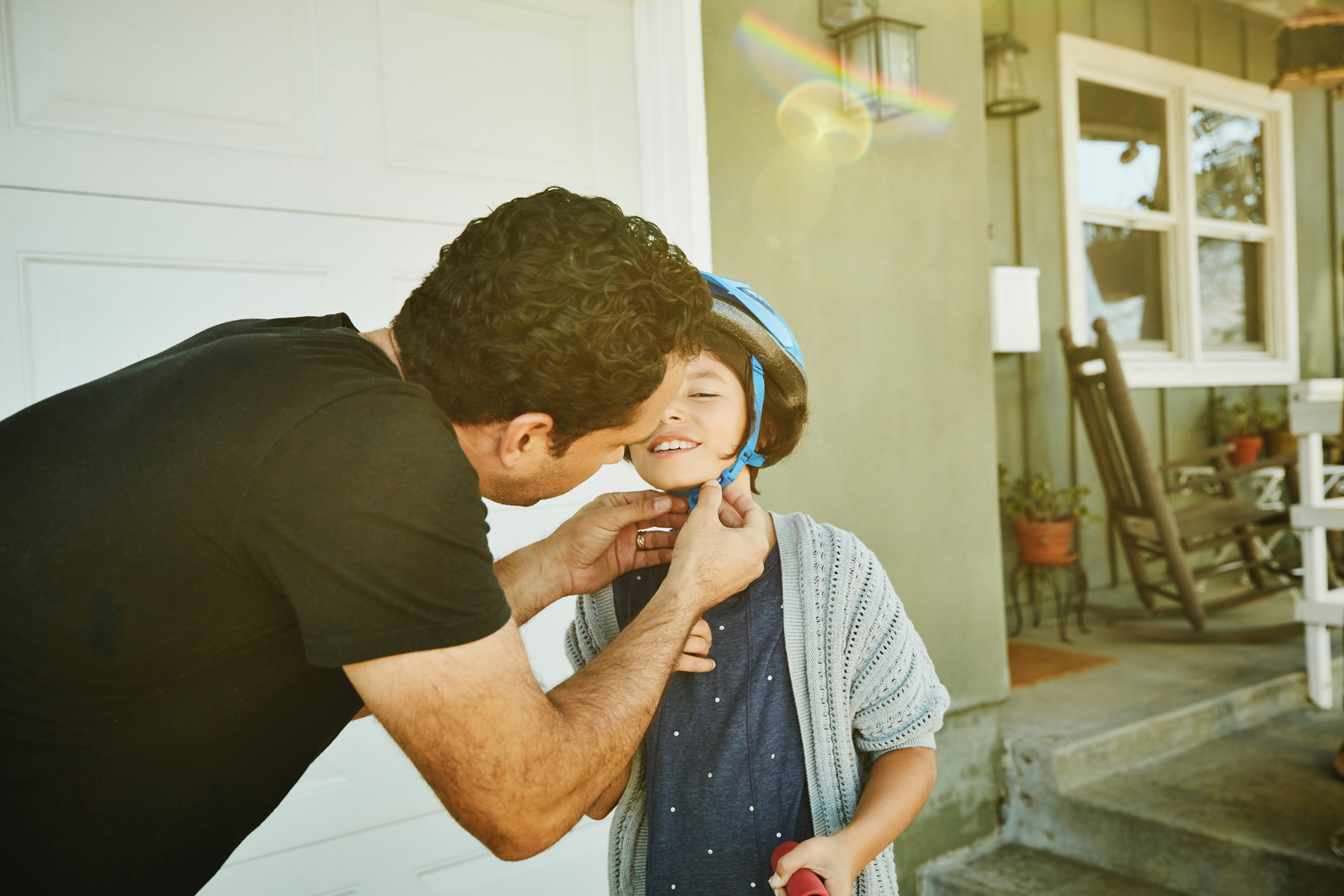 Parent helping a child fasten a bicycle helmet.