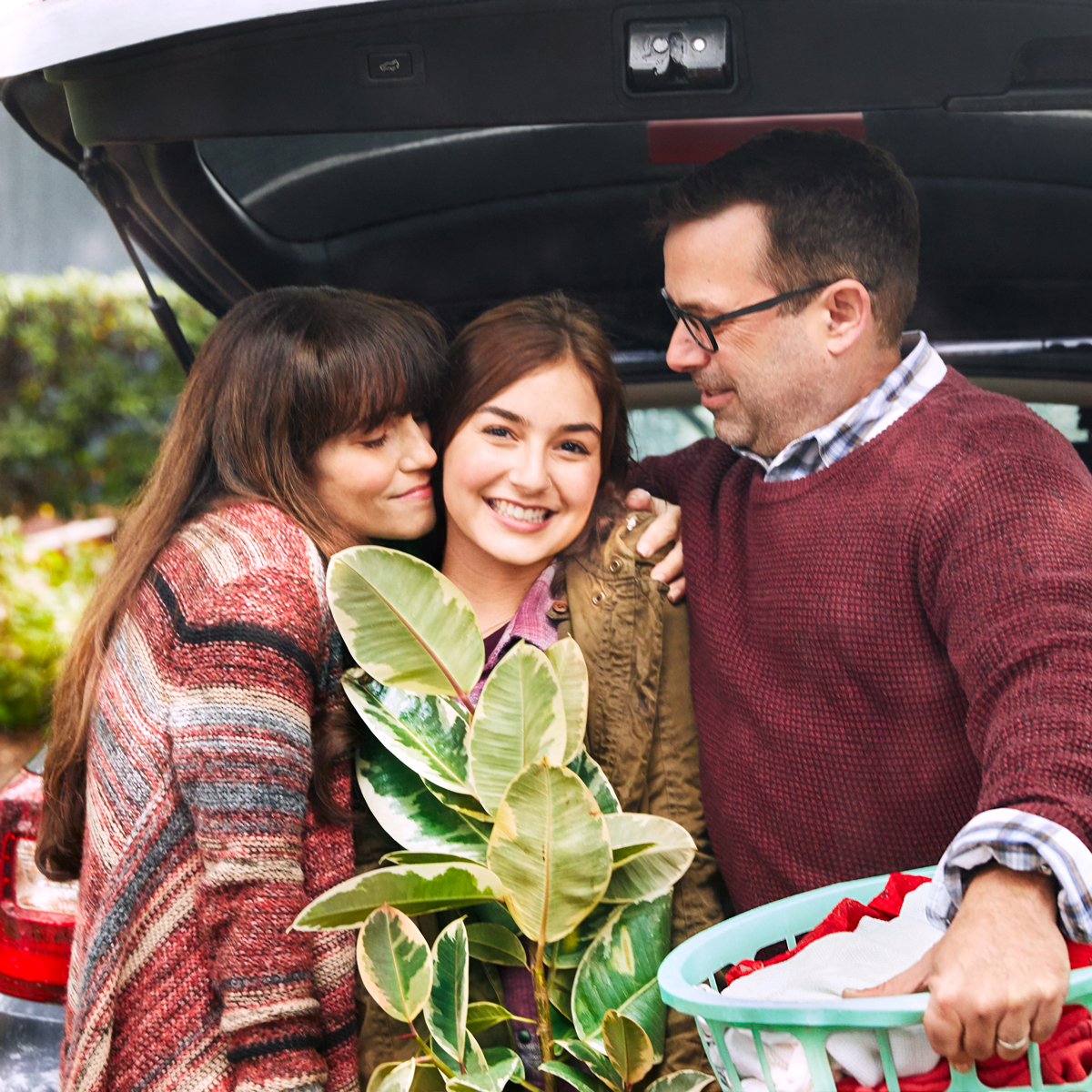 Parents embracing their daughter while helping her move.