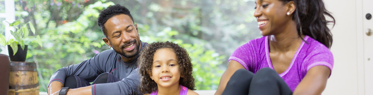 Parents and young daughter in exercise gear smiling 