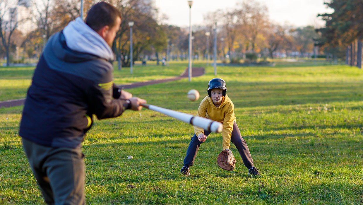Dad hitting baseball to son