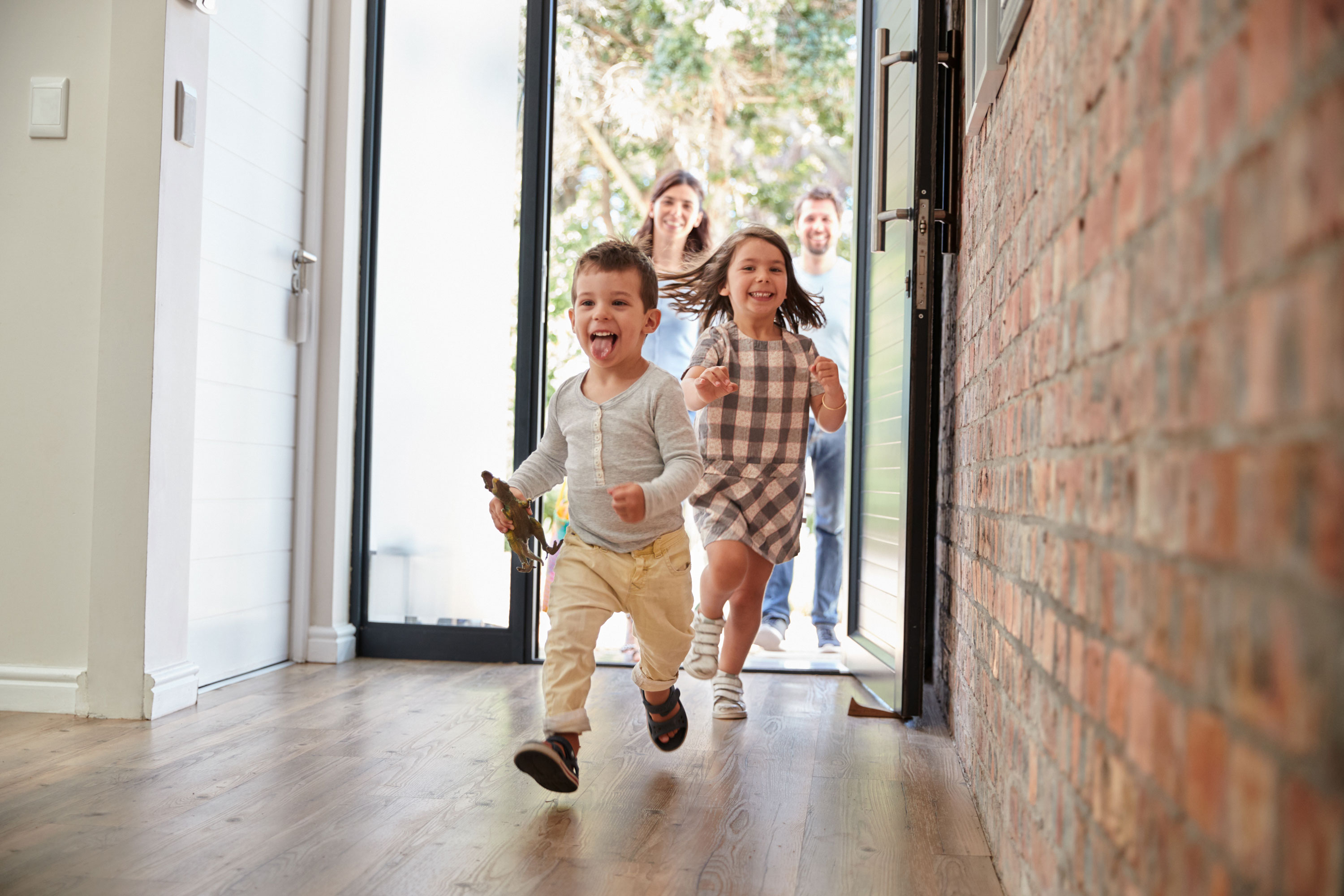 Children running into a home while parents follow behind.
