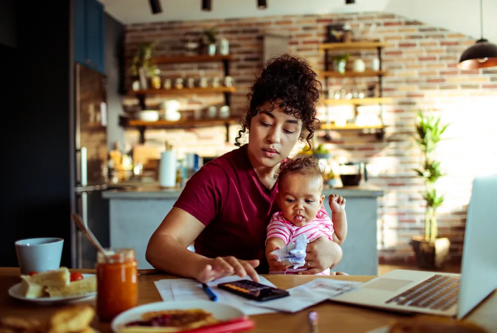 Young mother working on phone with baby on lap