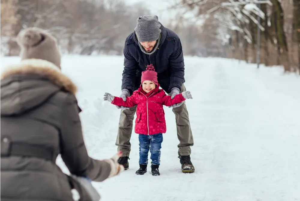 parents playing with young daughter in the snow