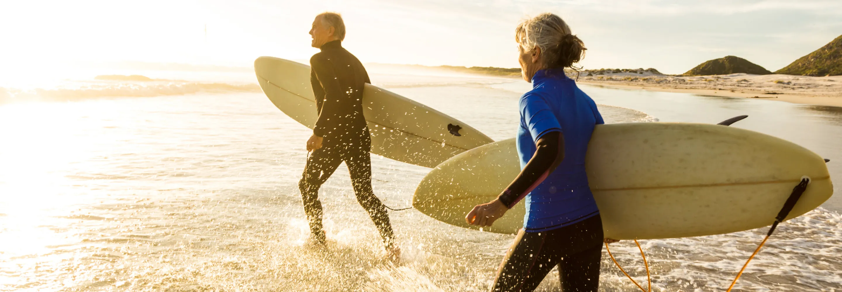 Mature couple heading out to surf