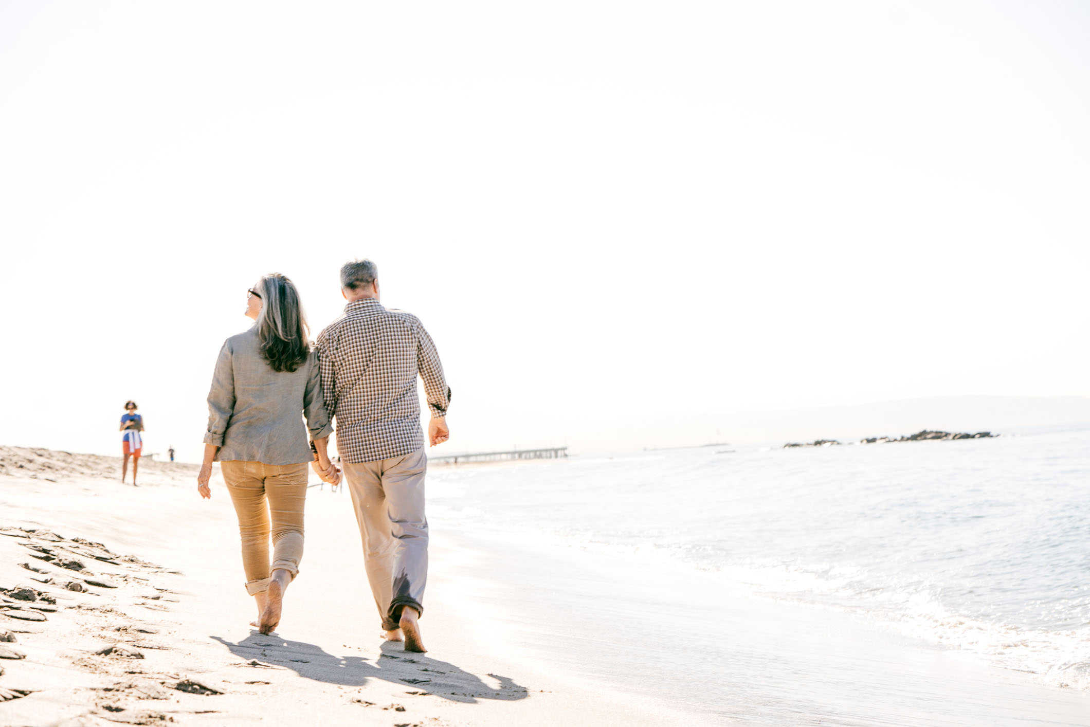 senior couple walking down the beach