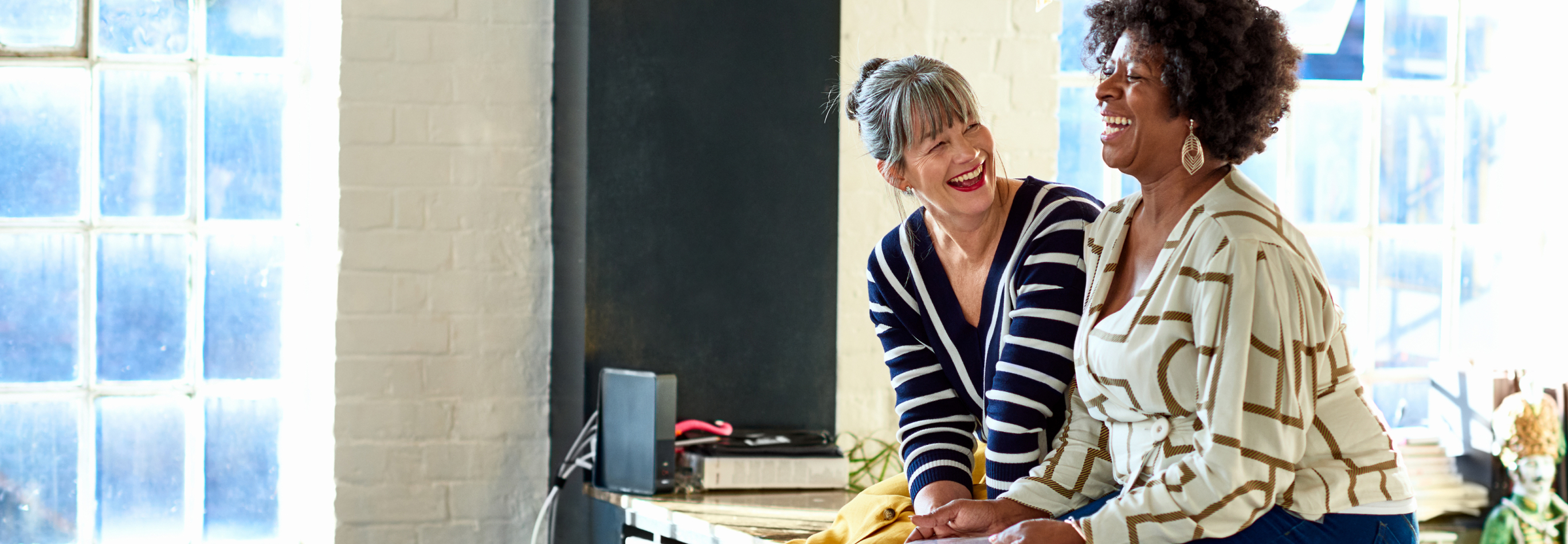 Mature women laughing together in stylish loft apartment