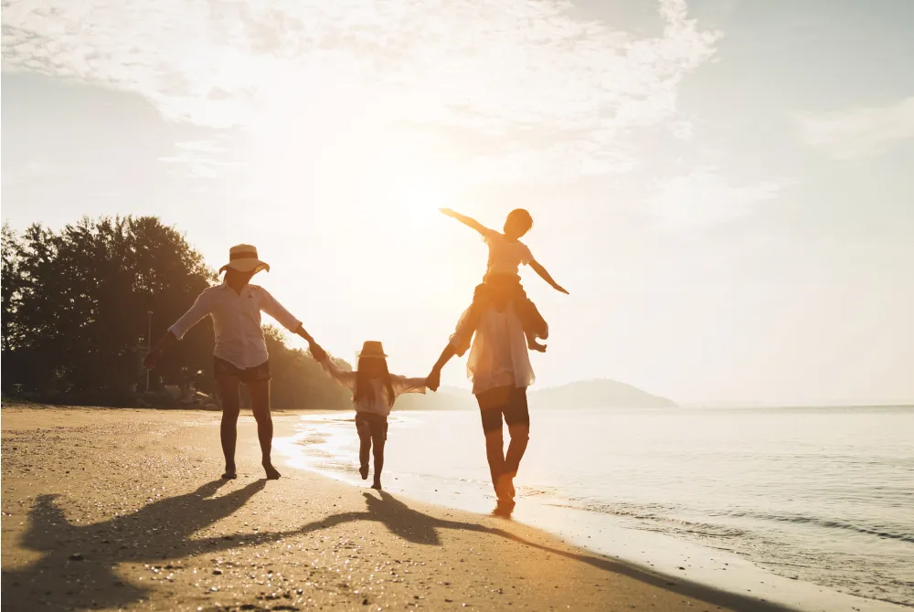 family of four walking on the beach at sunset