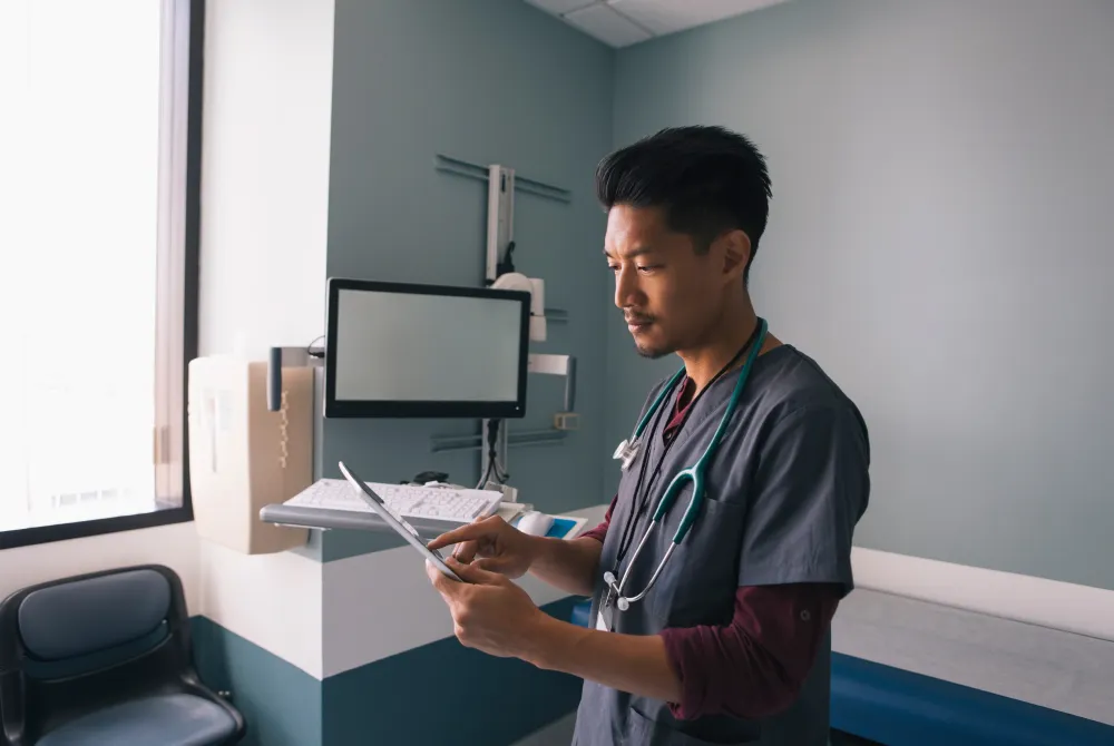 male nurse looking at information on a tablet
