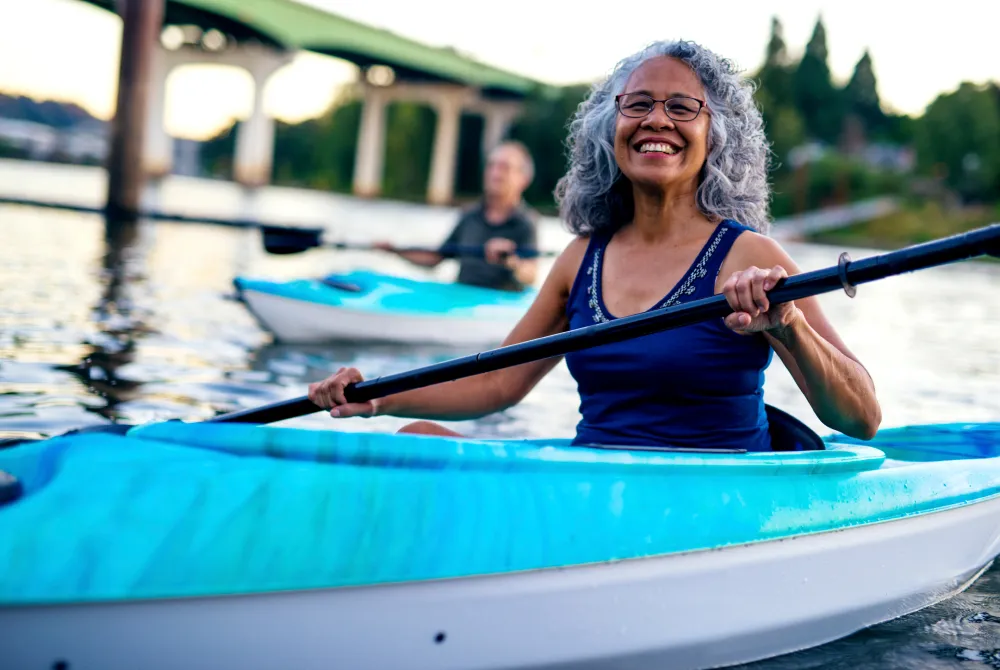 mature woman kayaking on a river with man in the background