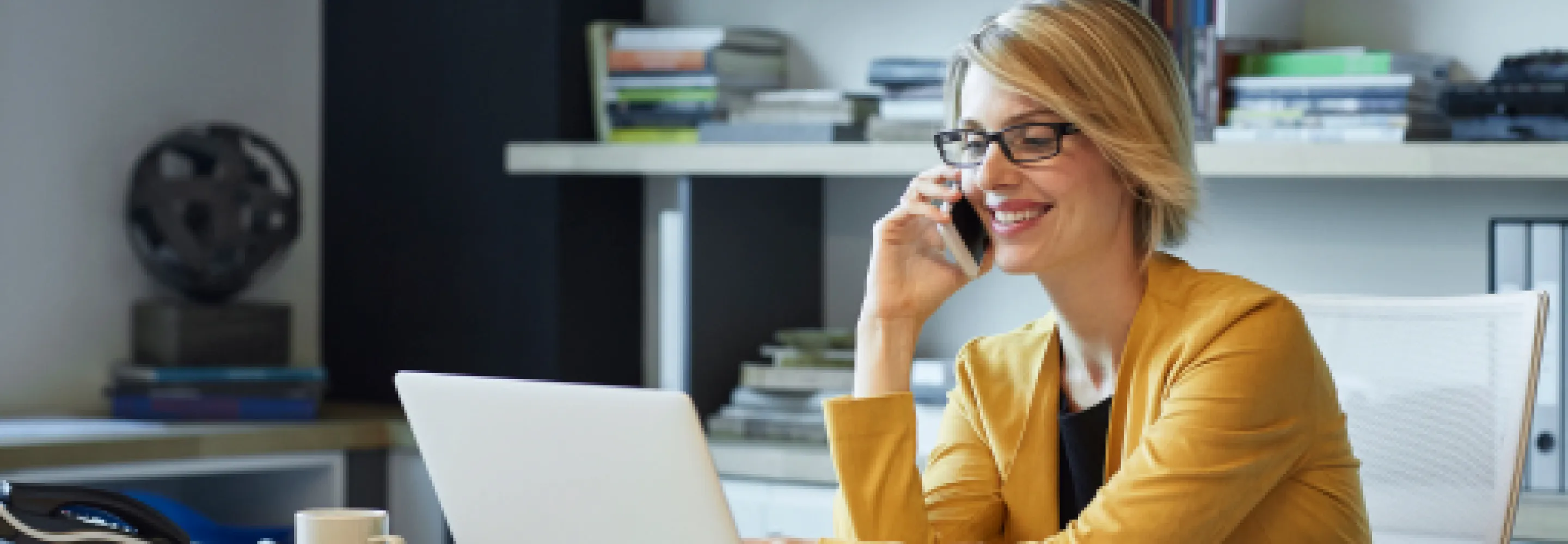 Businesswoman using laptop and phone at desk