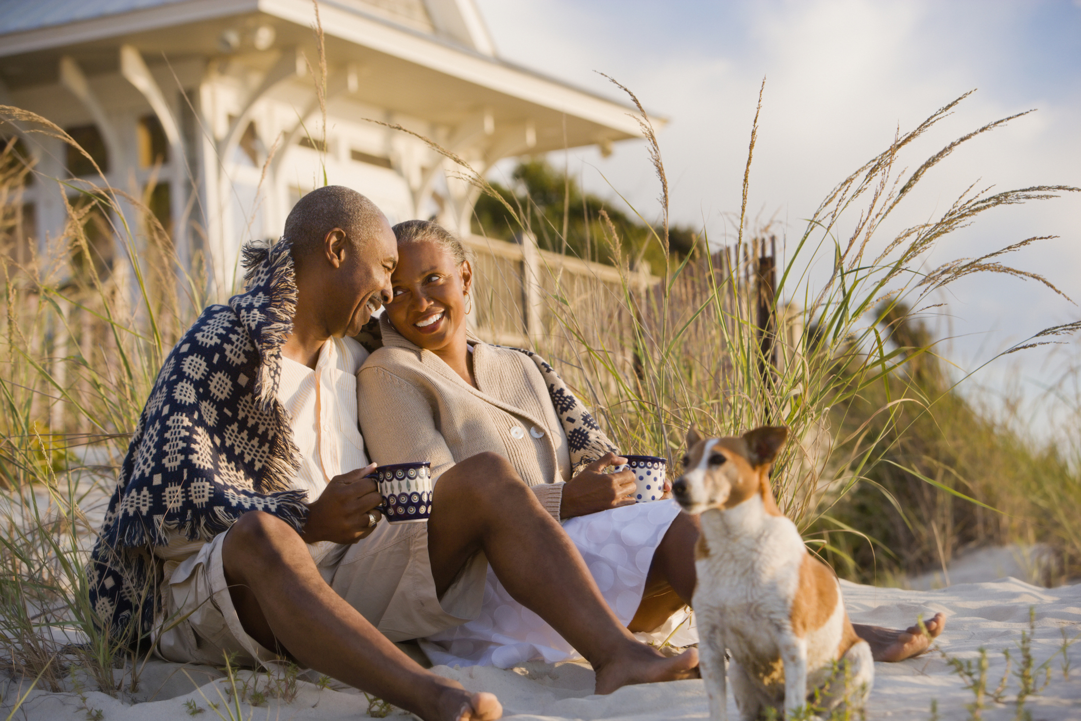 retired couple sitting on the beach with their dog