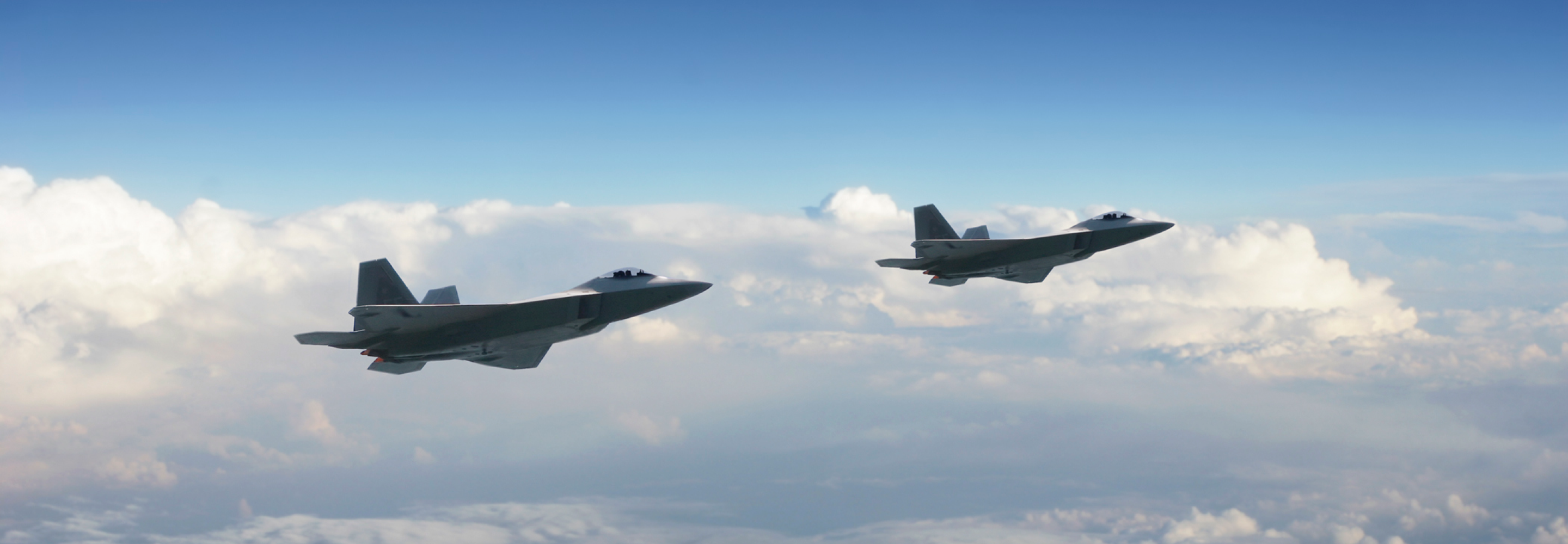 two military jets above the clouds