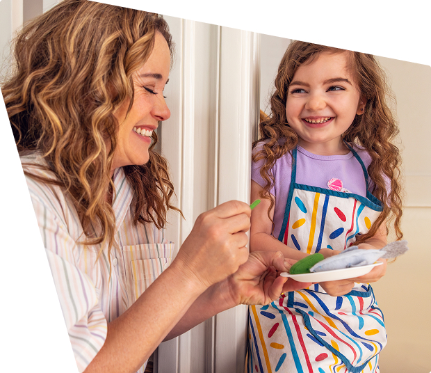 An adult helps a young child paint, representing New York Life Golden Futures Awards and Scholarships supporting children’s creativity and future potential.