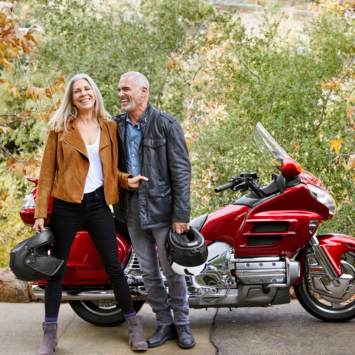 Couple standing beside a motorcycle outdoors.