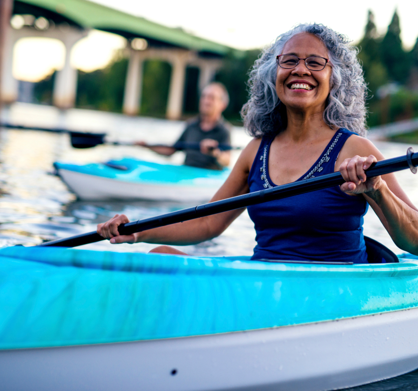 •	mature woman kayaking on a river with man in the background