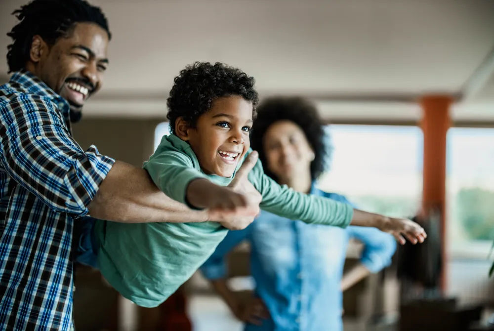Young father holding up young son with mother in the background