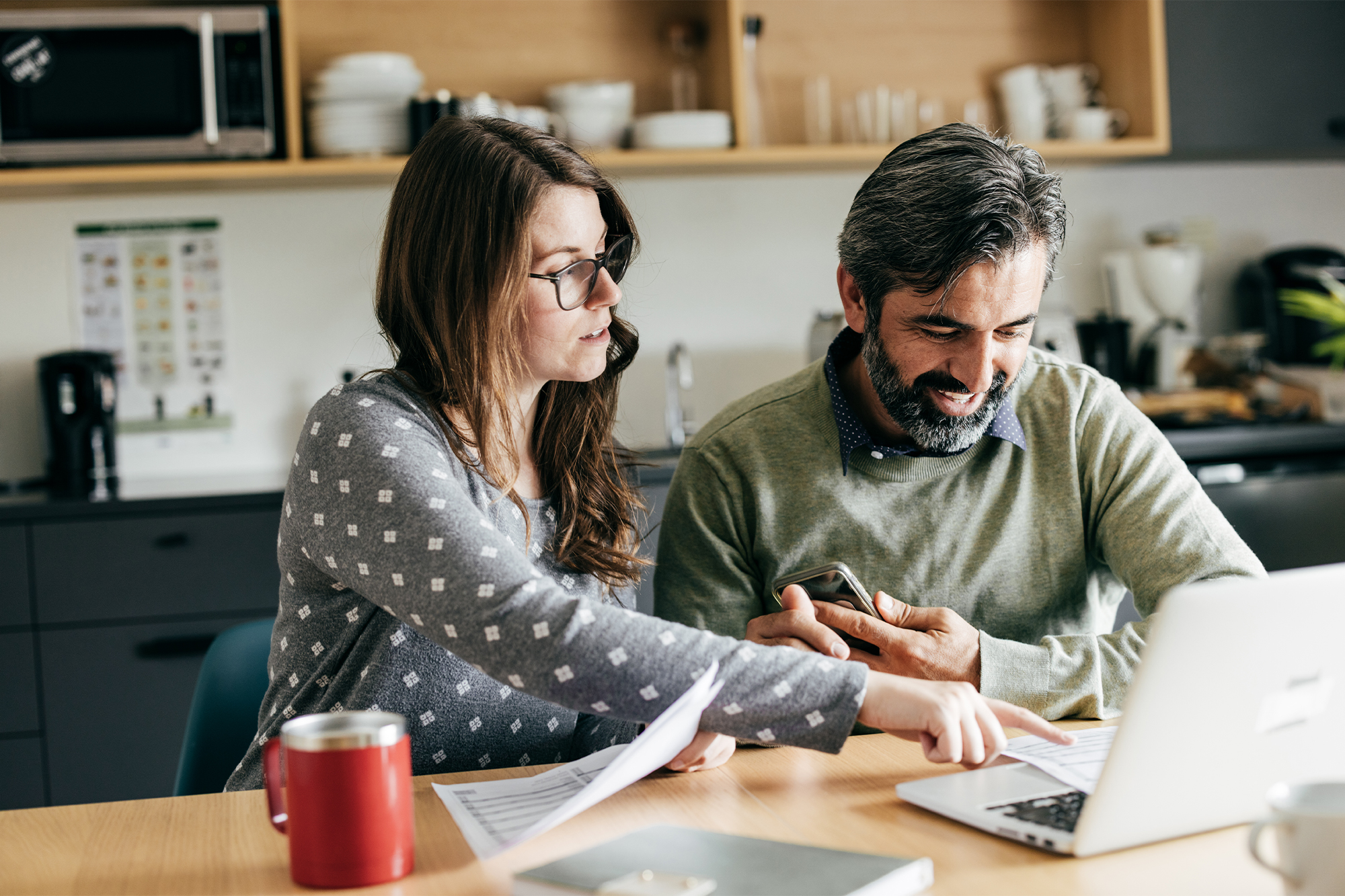 Couple reviewing financial documents and information on a laptop.