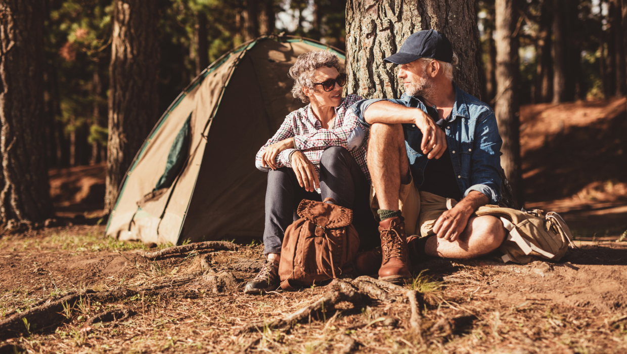Retired couple sitting in front of a tent while camping