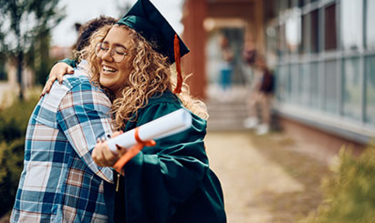 woman hugging a high school graduate holding her diploma