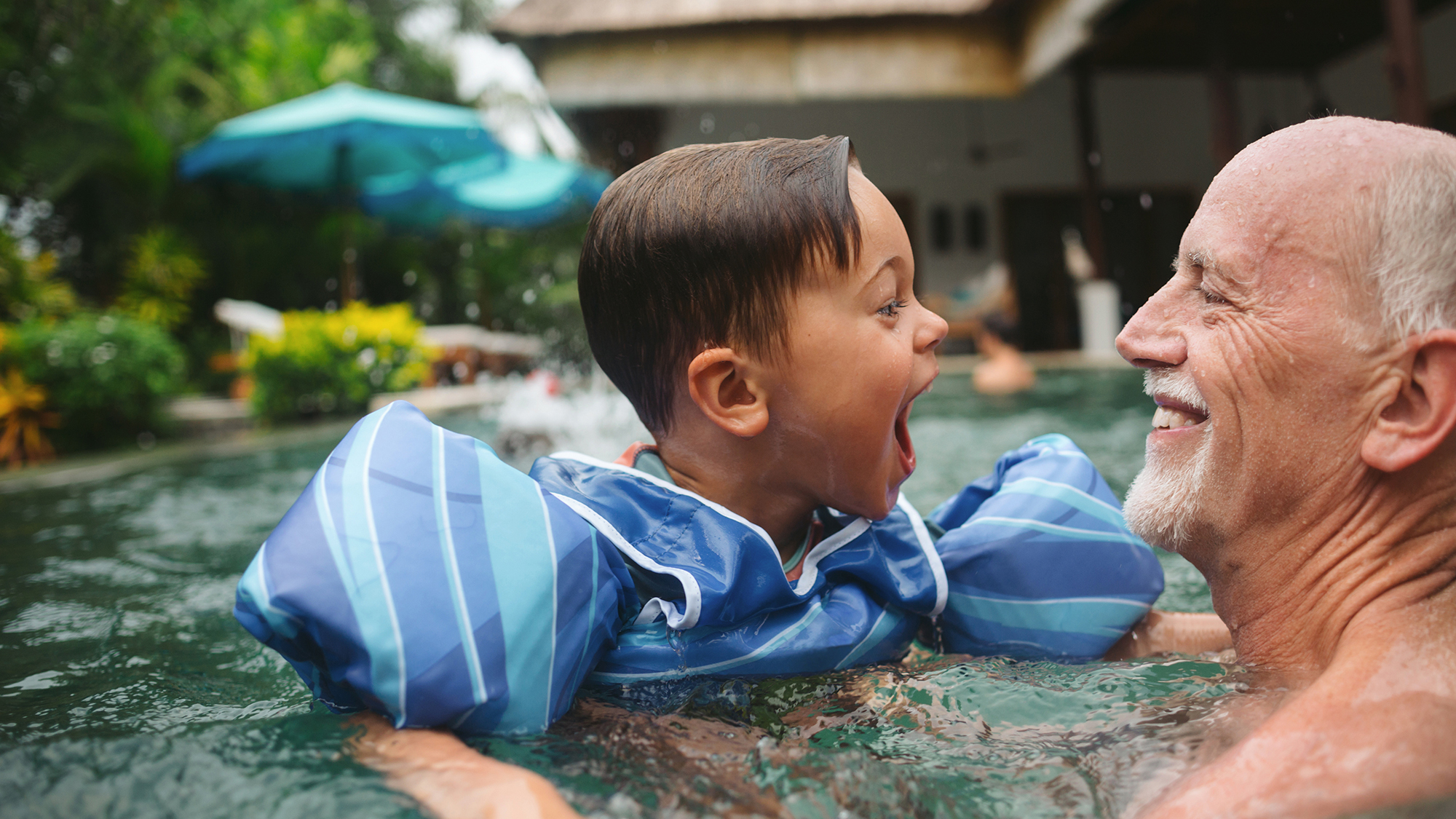 Grandfather and young child enjoying time together in a swimming pool.