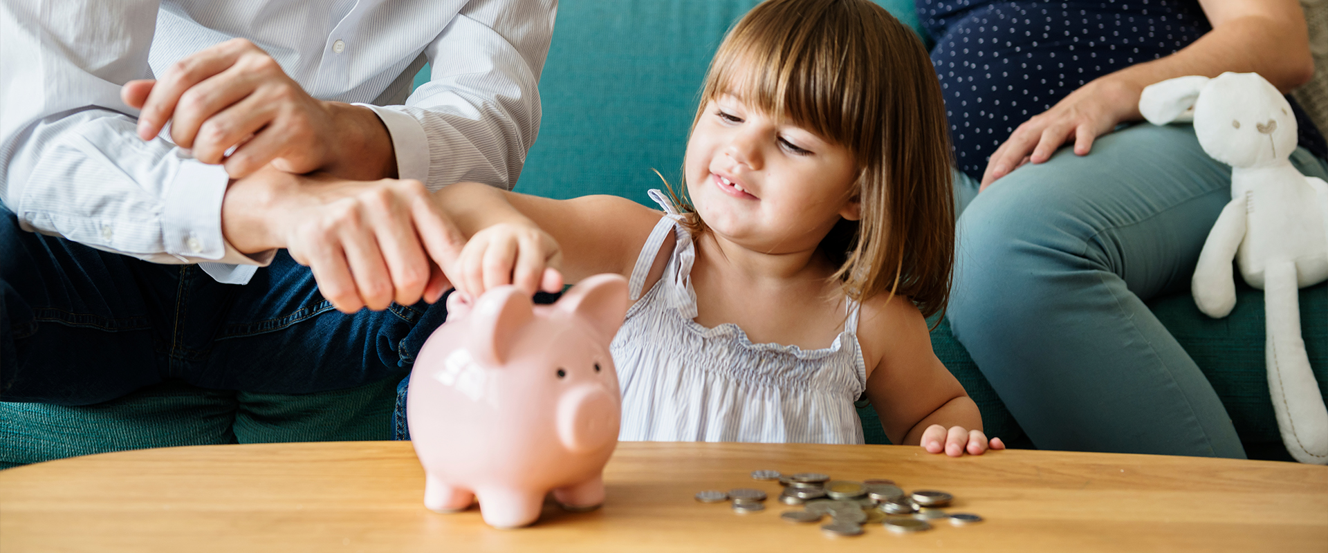 little girl putting coins in a piggybank