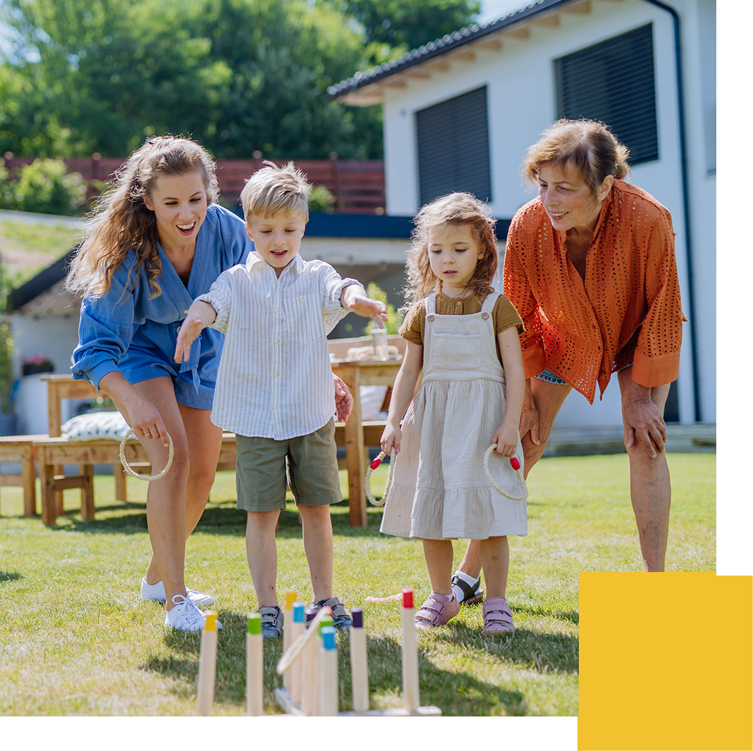 Multi generation family playing throw a ring game when grilling outside on backyard in summer at garden party.