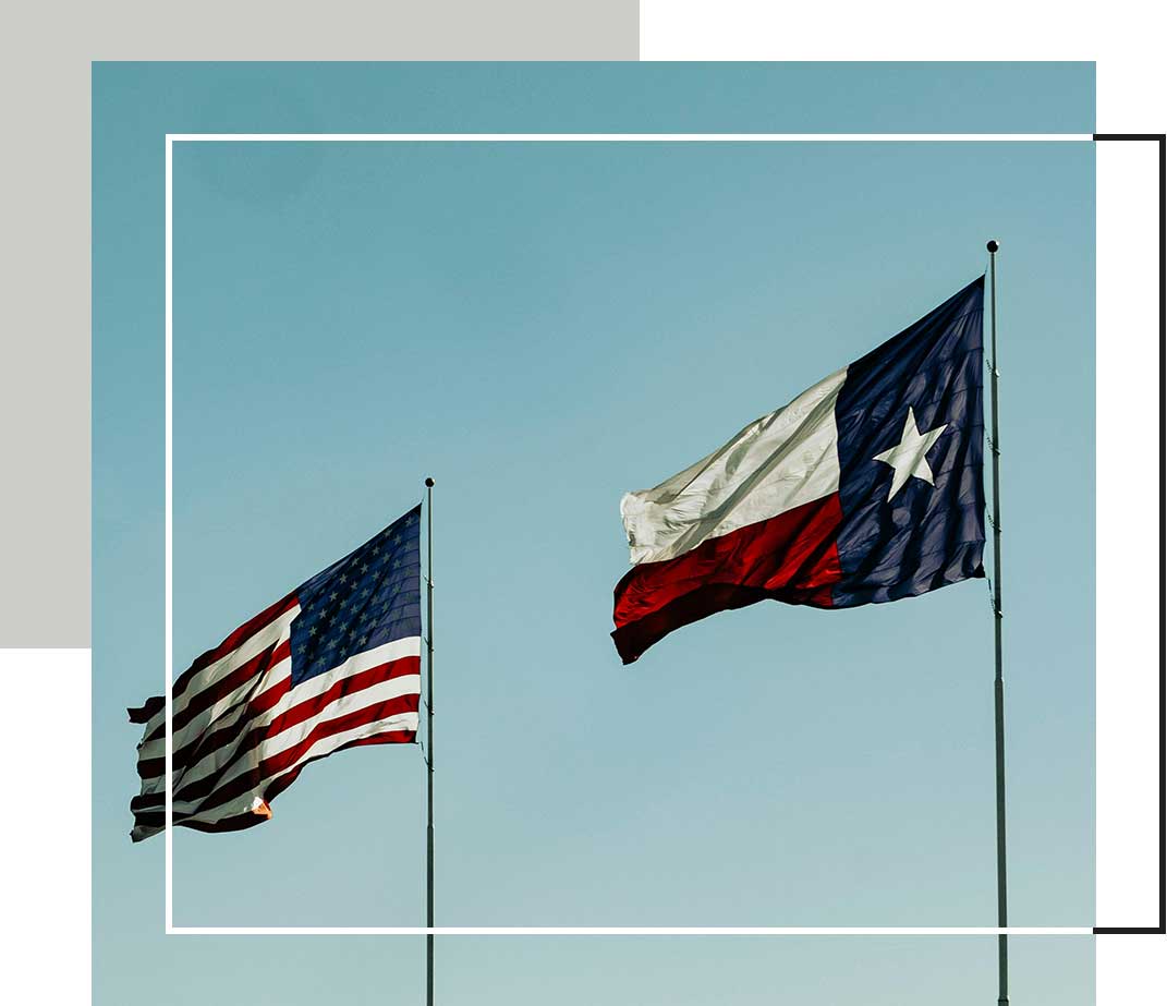 The U.S. flag and Texas state flag wave side by side against a clear blue sky.