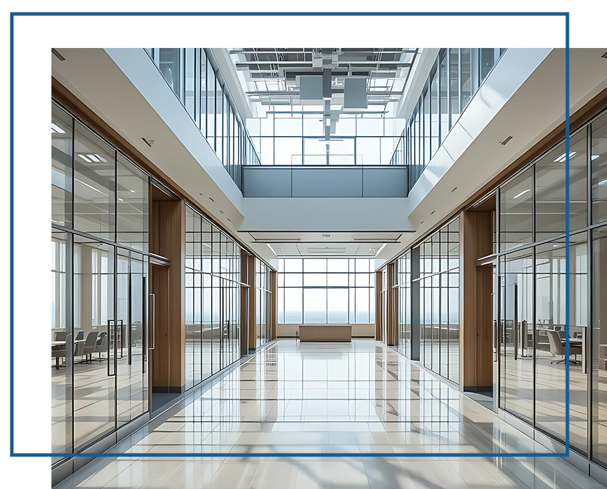 Bright, modern office corridor featuring glass-walled meeting rooms, wooden accents, and a skylight flooding the space with natural light.