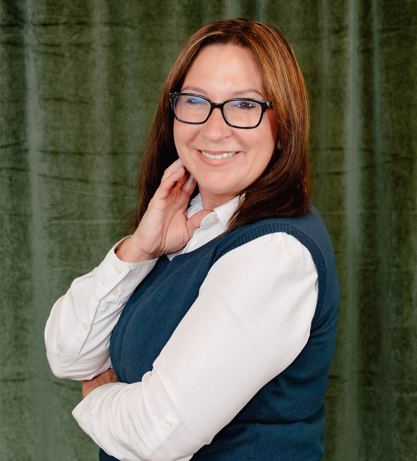 Carla Jagodzinski headshot wearing a green vest o in front of green background