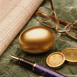 Golden egg alongside gold coins, financial documents, glasses and a purple fountain pen