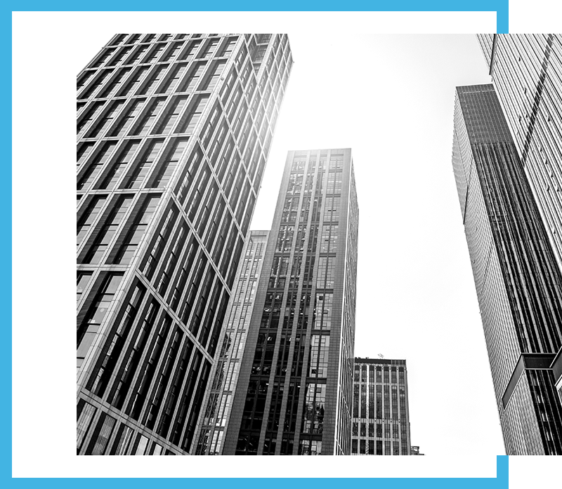 Black and white image of modern skyscrapers rising into a bright sky, framed by a bold blue border.