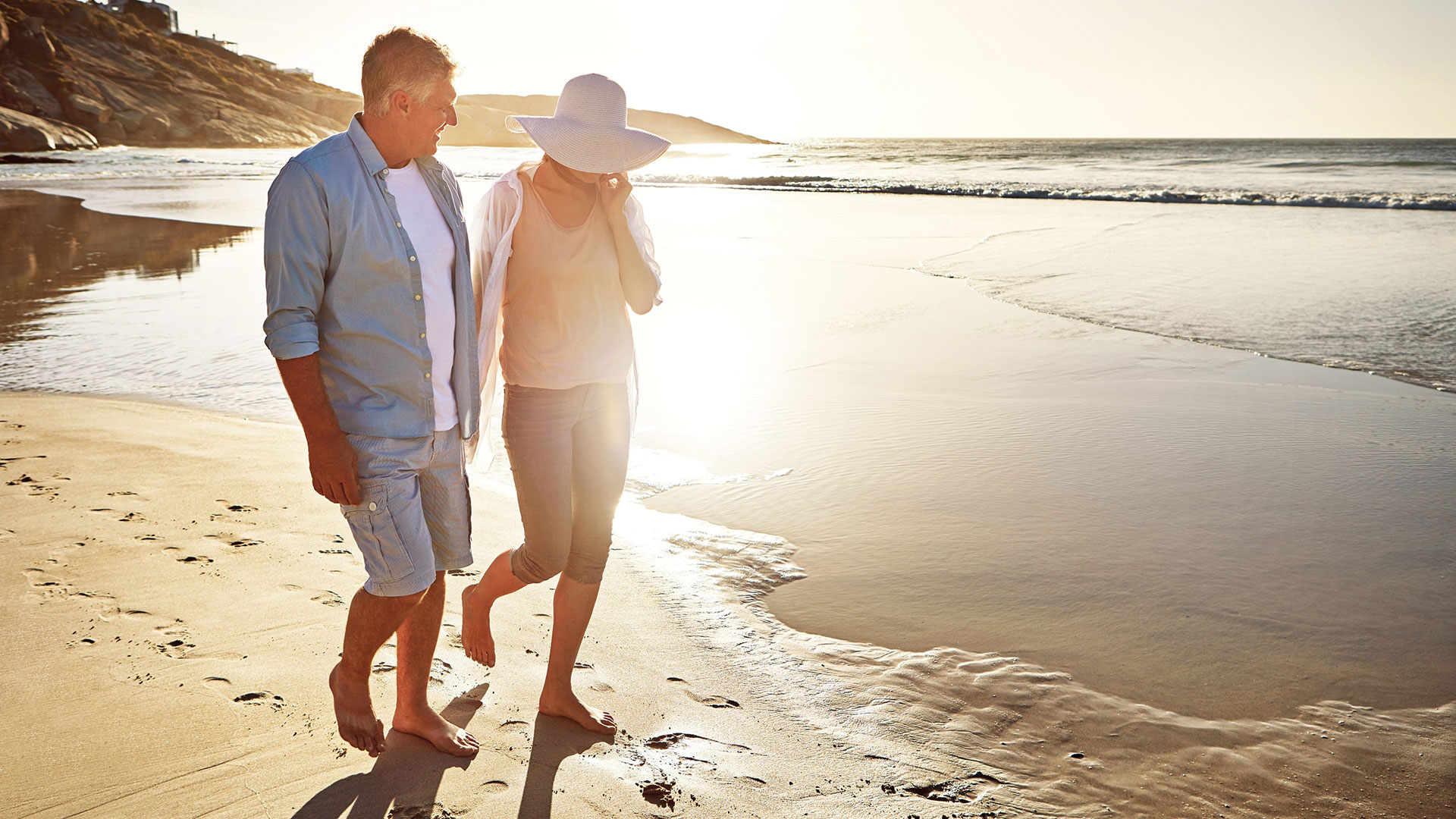 Pre-Retiree couple walking alongside the beach