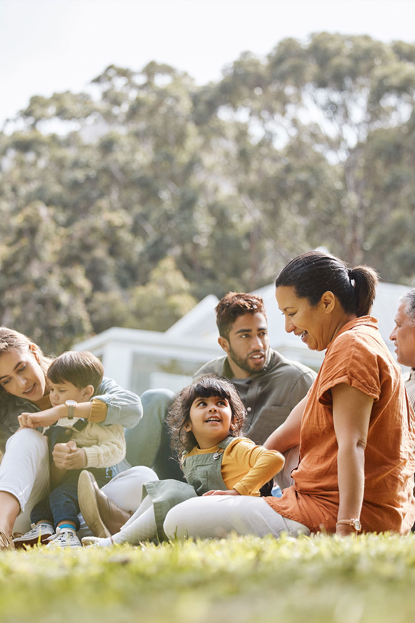 Children, parents and grandparents talking and sitting outside on the grass