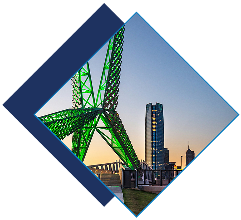 View of the illuminated Skydance Bridge with downtown Oklahoma City skyline at sunset