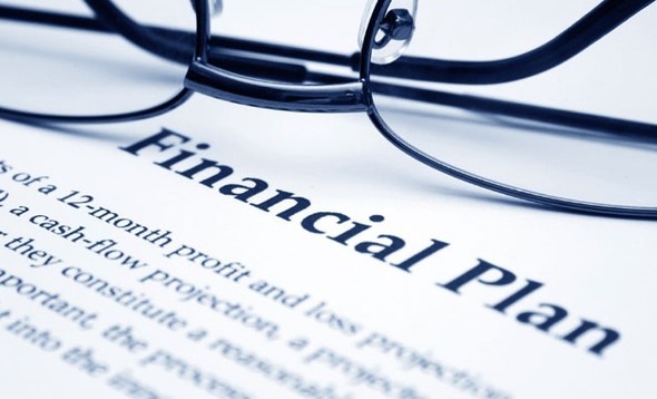 detail financial plan document with glasses on top