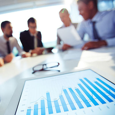 detail of tablet with bar graph conference table people meeting in background