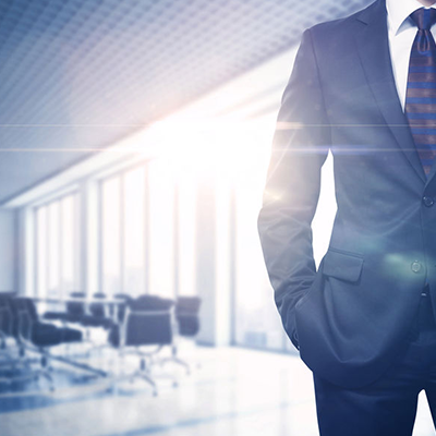 detail of man in suit with glass wall conference room in background