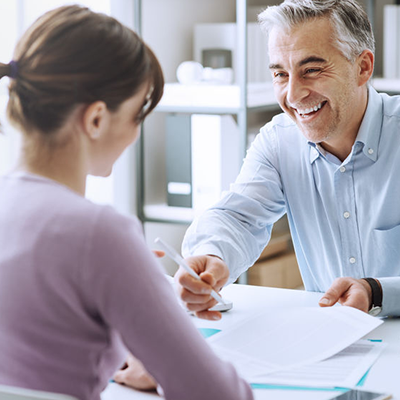 woman seen from behind man sitting across desk smiling with documents