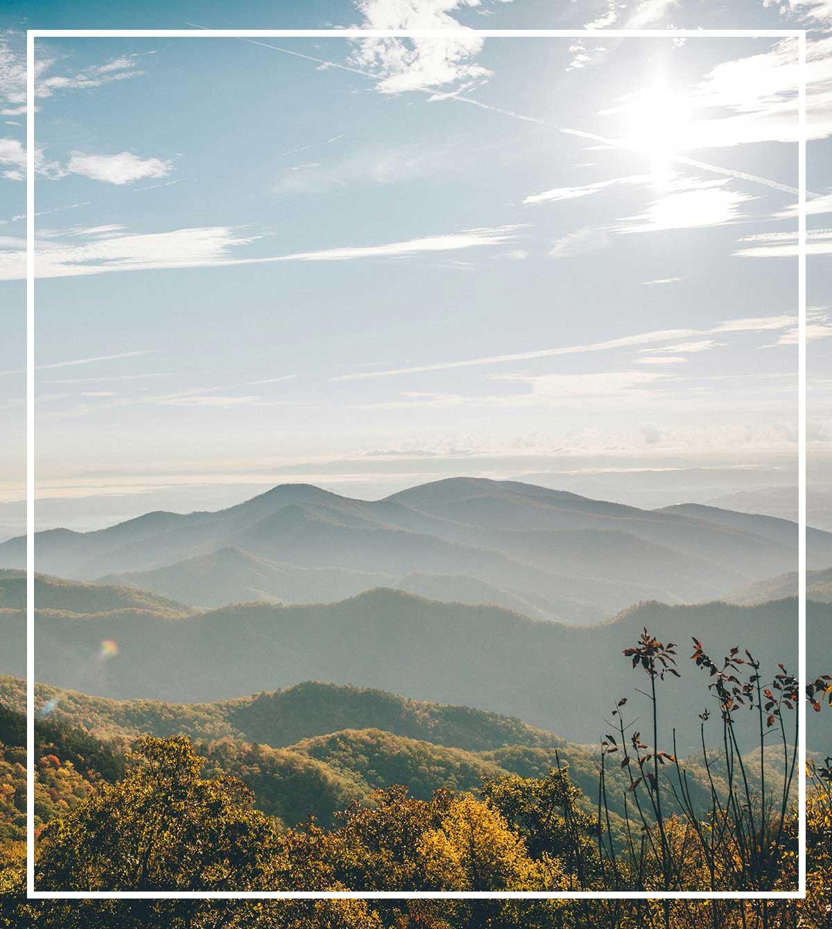 Sunlit mountain ridges layered in the distance beneath a bright blue sky.