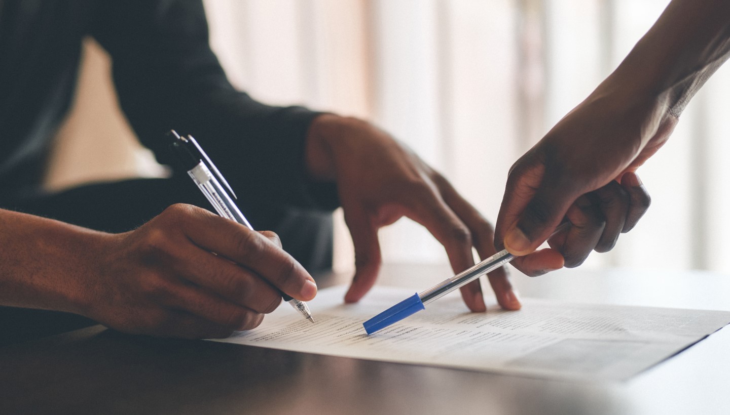 Sanding Person Helping Sitting Person Fill Out a Form Image