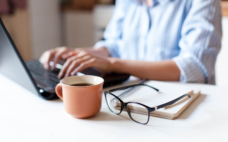 Person Working on Laptop at Table Image