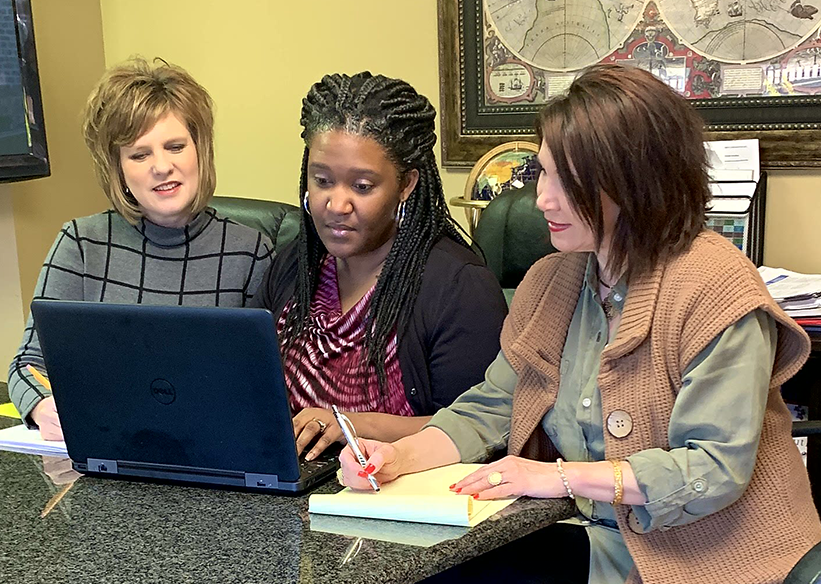 Lori, Pamela and Angela Seated at Desk With Laptop Image
