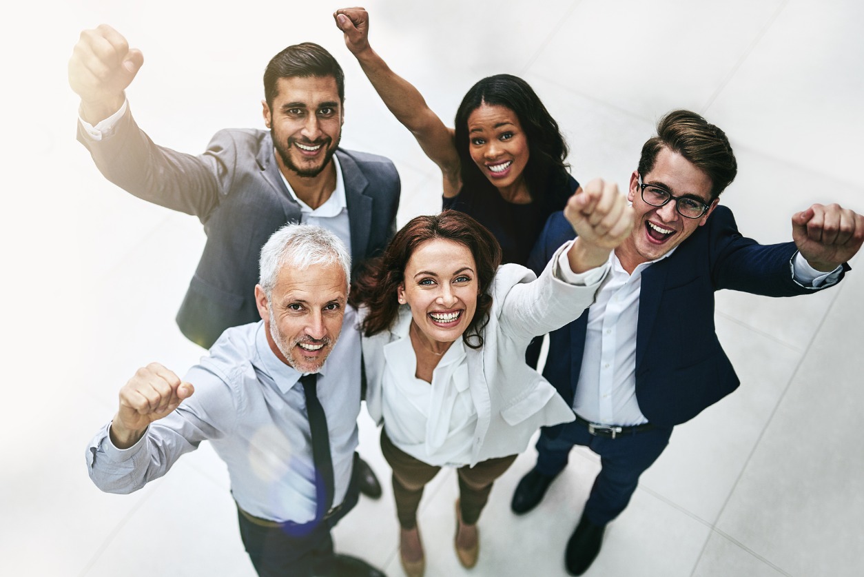 Group of 5 Smiling and Raising Their Fists Shot from Above Image