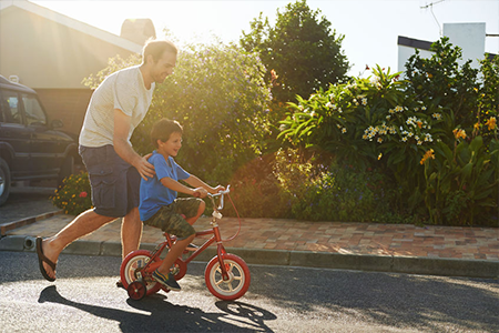 Father Teaching Son How to Ride a Bicycle Image
