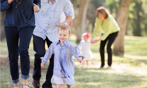 small child running outside with family
