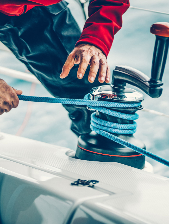 close up sailor winding rope on winch with handle