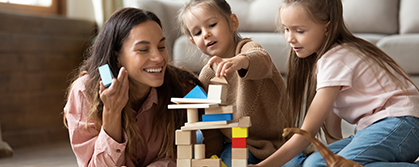 young mother smiling building blocks with young children