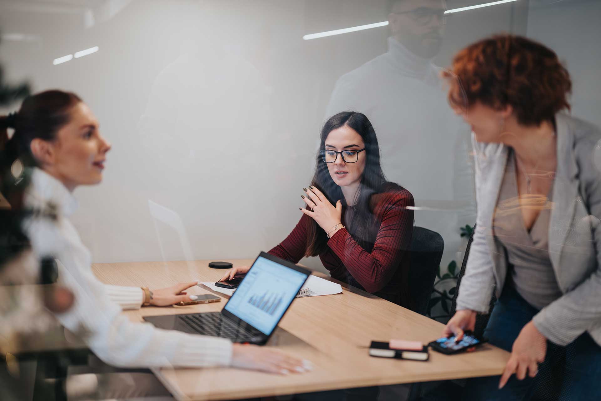 In a modern office setting, three professionals engage in a dynamic discussion, highlighting teamwork and collaboration.