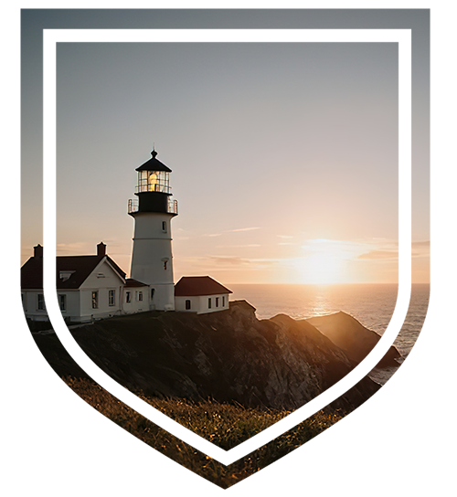 A lighthouse on a coastal cliff at sunset overlooking the ocean.